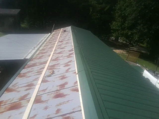 Old rusted panels beside newly installed green metal roofing — Wind Damage Roof Repair by Roofing Brothers in Hometown