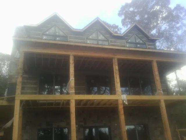 Dormers and porch framing on a large log home under construction — Roof Coating work by our crew in Hometown