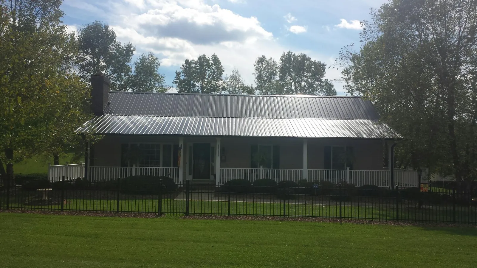 Gray metal roof on a brick ranch with a full width front porch — Gutter Guard Installation work by our crew in Hometown