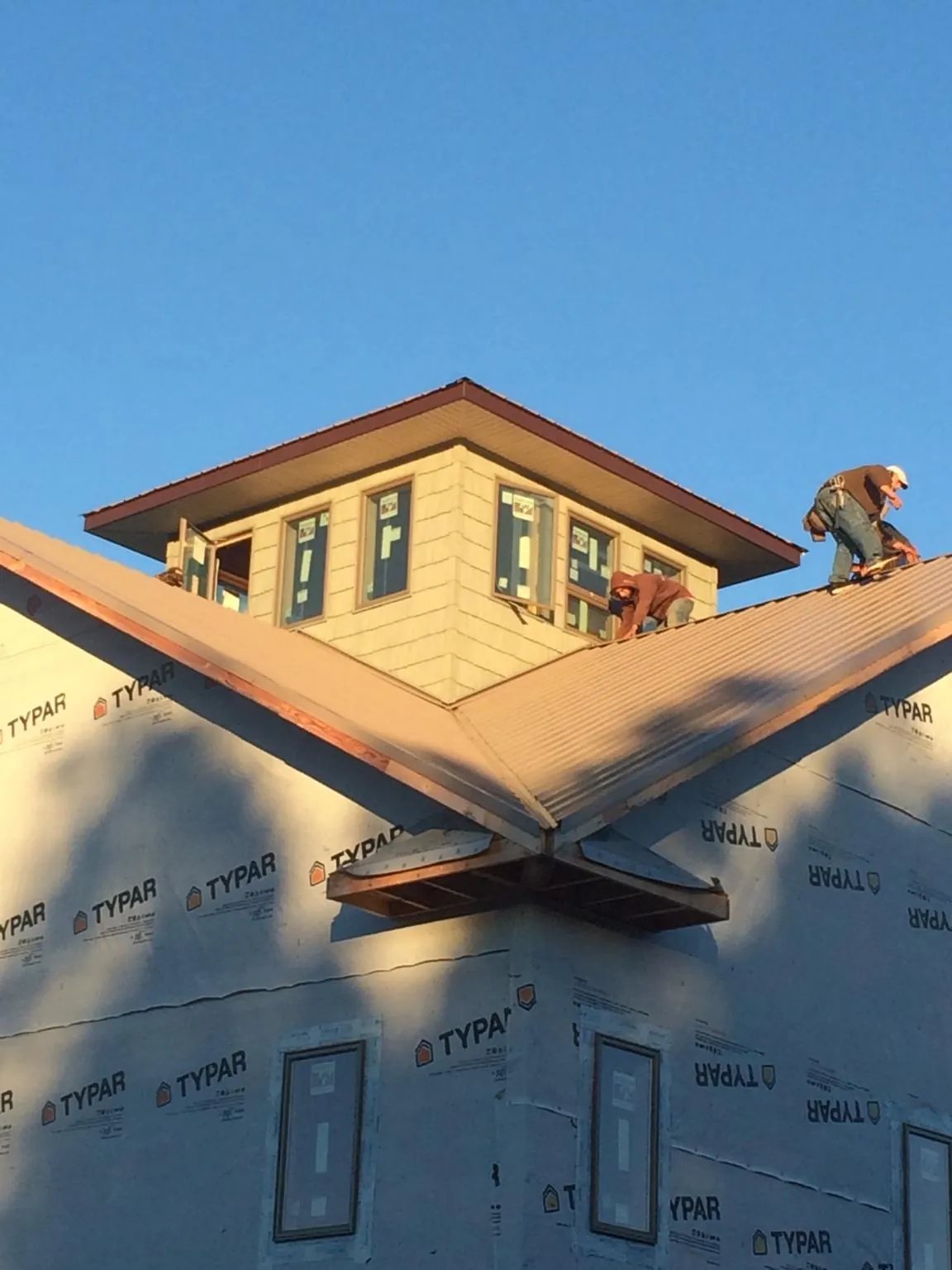 Roofers working around a rooftop cupola on a new metal roof at sunset — Roof Waterproofing in Hometown by Roofing Brothers